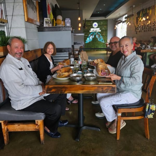 Four people smiling at a table with plates of food and drinks at A Taco by Divino.