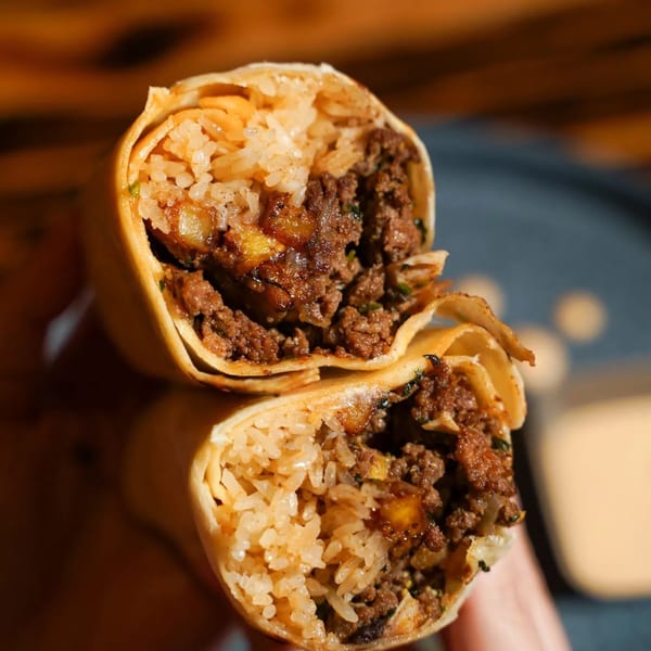 Two halves of a large burrito, revealing a filling of seasoned ground meat and rice.